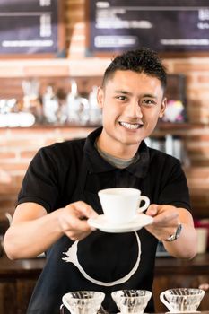 Asian Barista offering cup of drip brew coffee