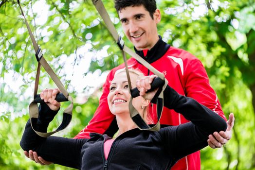 Sport woman with trainer at sling training