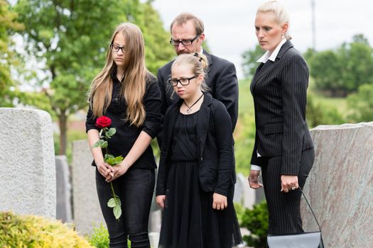 Family on cemetery mourning deceased relative