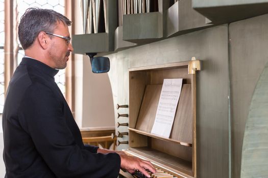 Pastor making music playing organ in church