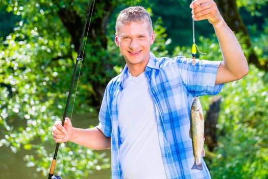 Sport fisherman showing catch dangling from fishing rod