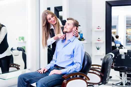 Man being shaved by barber woman