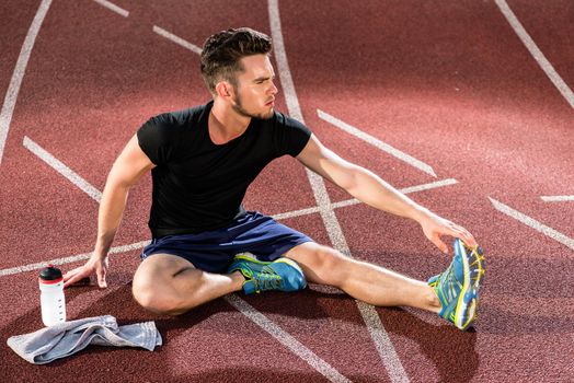 Athlete stretching on racing track before running