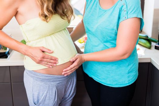Woman touching baby belly of best friend