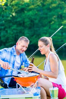 Man and woman having barbeque grilling fish 