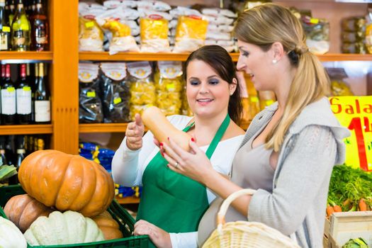 Woman buying pumpkin and vegetables in delicatessen