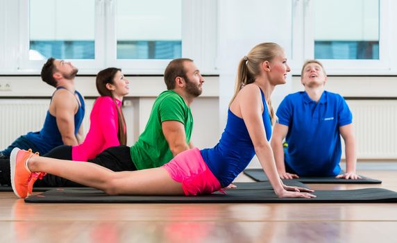 Recreational athletes doing yoga exercises in fitness gym