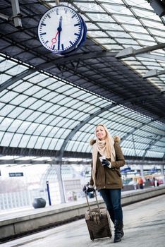 Woman looking at clock in train station as her train has a delay