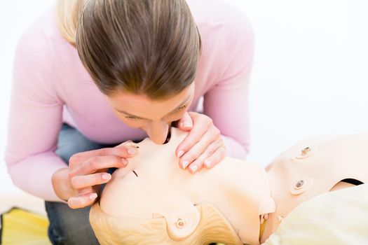 Woman training mouth-to-mouth breath donation on dummy