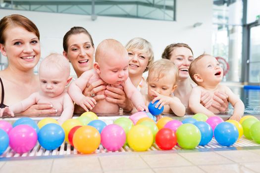 Group of moms and their little babies at baby swimming lesson