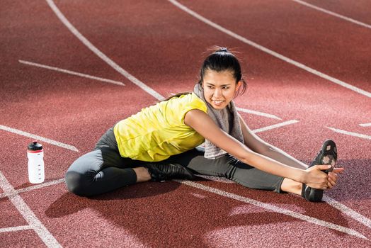 Woman sprinter doing warm up exercise before sprint