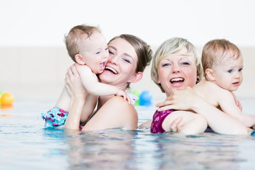 Mothers and their little children having fun at baby swim lesson