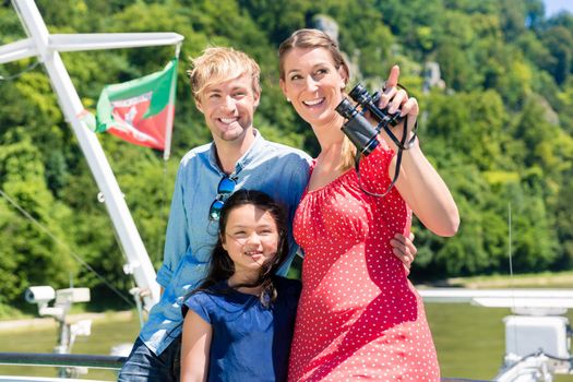 Family on river cruise with binoculars in summer