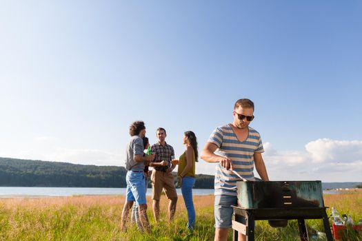 Clique of young people making BBQ at lake
