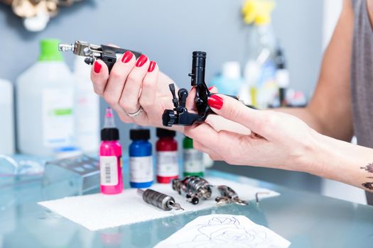 Close-up of the hands of a female artist preparing a professiona tattoo machine