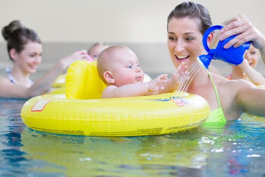 Mothers and kids having fun together playing with toys in pool