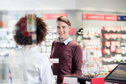 Young man smiling while buying an useful pharmaceutical product 