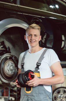 Portrait of a confident young auto mechanic holding a new air suspension system