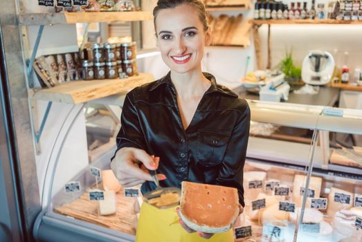 Beautiful woman offering cheese on delicatessen counter