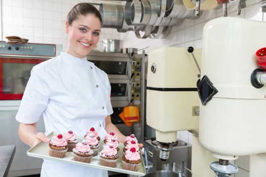 Proud confectioner showing muffins she baked