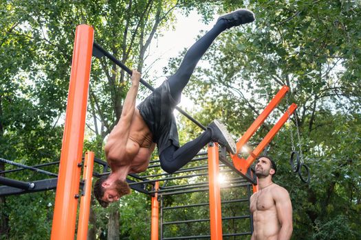 Shirtless bodybuilder hanging on horizontal bar during workout