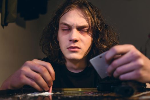 Drug addicted teenage boy holding a rolled bill while snorting