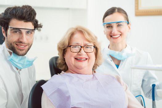 Dentists and patient in surgery looking at camera