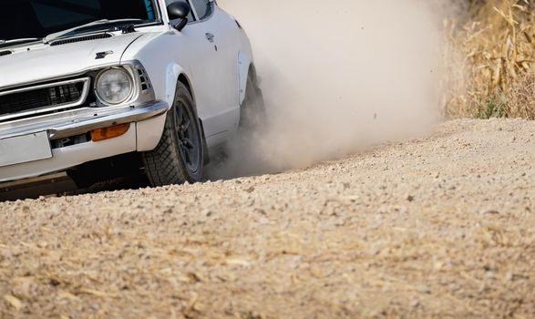 Classical rally racing car on dirt road.
