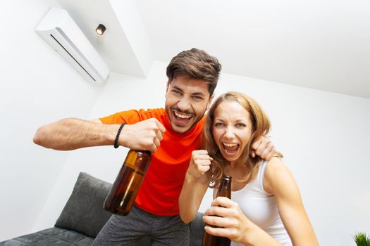 couple with beer bottles cheering and screaming