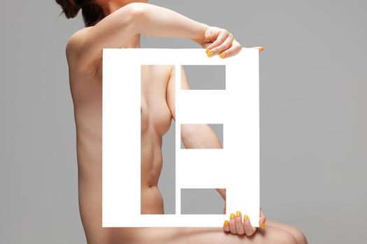 nude girl holding stencil letter e