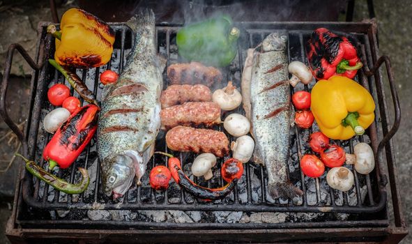 Barbecuing an assortment of red, yellow and green capsicum,  mushrooms, and trout fish