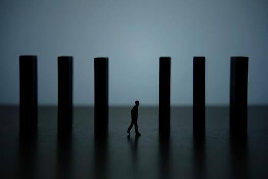 Business strategy conceptual photo – silhouette miniature of businessman walking in the middle of barrier wall