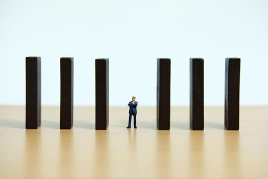 Business strategy conceptual photo - Miniature of businessman walking in the middle of barrier wall
