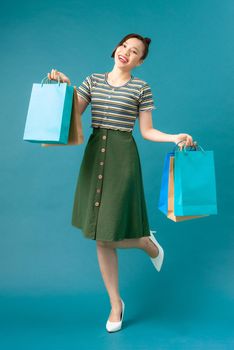 Girl stands on one leg and holds purchases in her hands after shopping