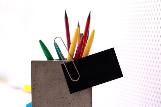A concrete organiser with office supplies in it and a business card