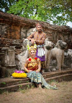 Portrait Of Smiling Young Woman In Balinese Traditional Clothing Holding Flower Bouquet At Temple