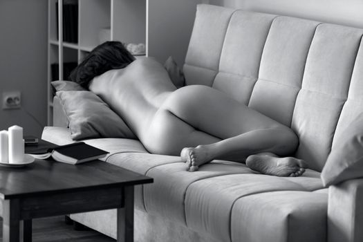 Naked woman sleeping on a sofa, daytime sleep 