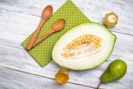 Cut melon with honey and green pear on wood