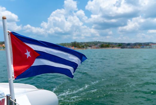 Cuba flag waving on boat at sea near Cuban coastline