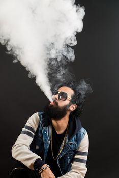Young man with beard vaping an electronic cigarette upwards. Vaper hipster smoke vaporizer.