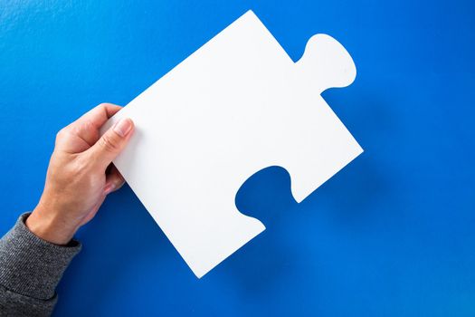 man hands holding big paper white blank puzzles on a blue background, concept of business