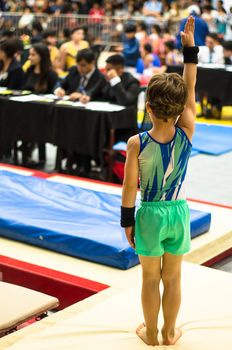Portrait of a gymnast child waving to the jury
