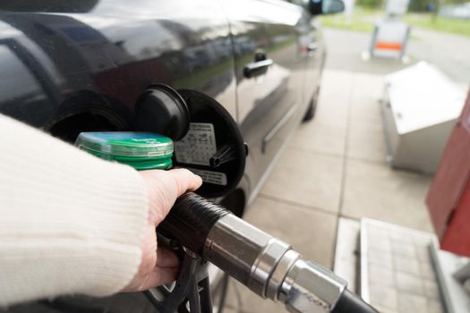 Female hand fill gasoline in a car with gas pump nozzle