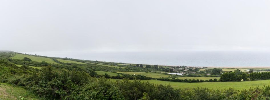 A South Dorset coastline near Weymouth, England. With meadows, clouds and deep blue sea. Panorama and banner