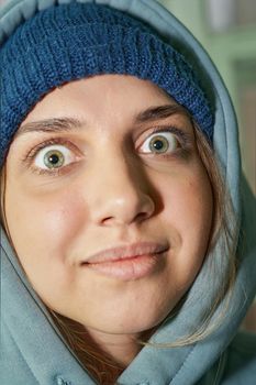 Young beautiful girl with big eyes looking at camera in a sweatshirt with a hood