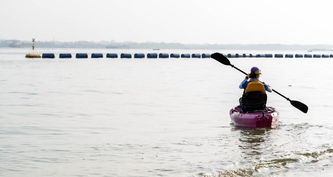 Rear view of woman paddling kayak. Paddling the canoe or small boat. Kayaking, canoeing, paddling 