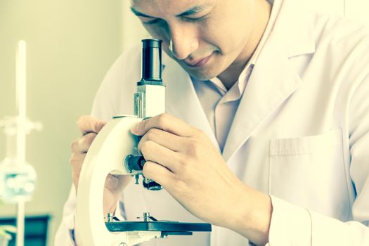 Asian scientists or chemists use a microscope.