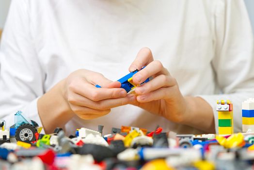 Close up of child's hands playing with colorful plastic bricks at the table. development of fine motor skills in children, favorable for the development of brain activity. Developing toys