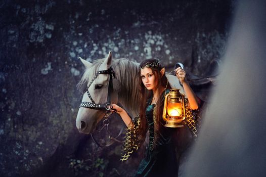 Young female elf walking with her horse holding a lantern