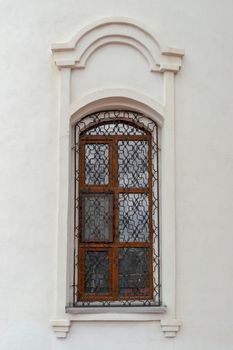 A window with a beautiful grille in the old Orthodox church. Outdoors, building fasade front view.